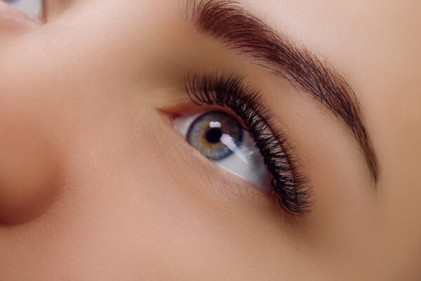 Photo eyelash extension procedure woman eye with long blue eyelashes close up selective focus M Curl Classic Lashes